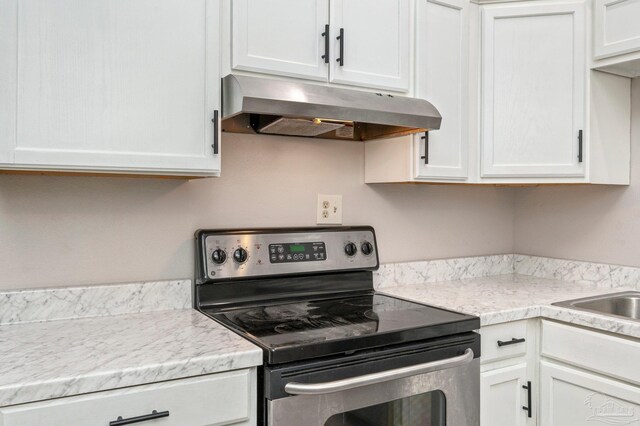 kitchen featuring light stone countertops, stainless steel range with electric cooktop, and white cabinets