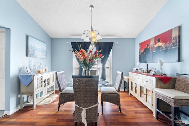 dining space featuring vaulted ceiling, a textured ceiling, wood finished floors, a chandelier, and baseboards