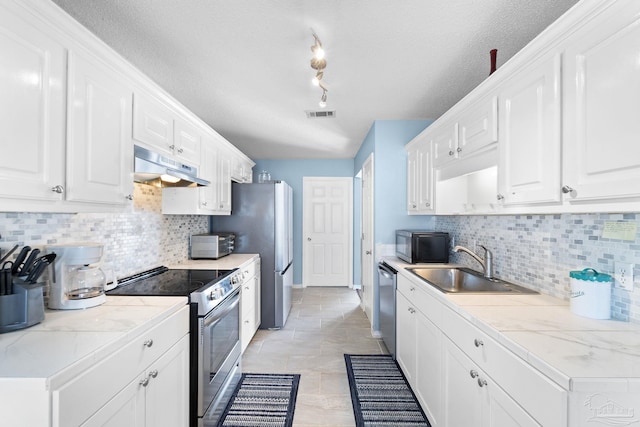 kitchen featuring under cabinet range hood, white cabinetry, appliances with stainless steel finishes, and a sink