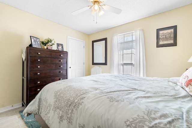 bedroom featuring light wood-type flooring, ceiling fan, a textured ceiling, and baseboards