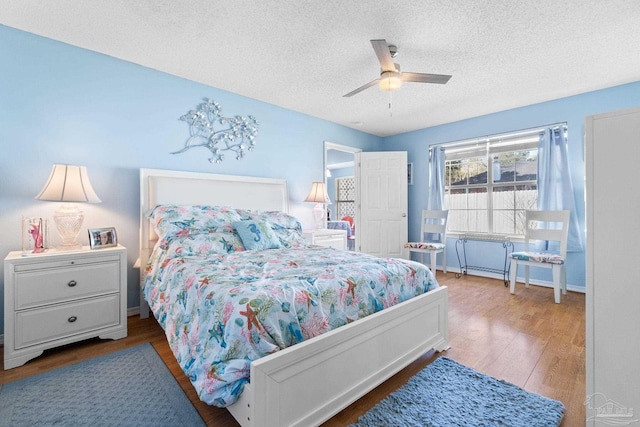 bedroom with baseboards, a textured ceiling, a ceiling fan, and wood finished floors