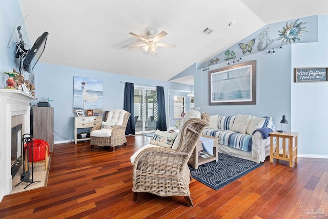 living area featuring a fireplace, visible vents, vaulted ceiling, and wood finished floors