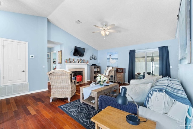 living area with a brick fireplace, visible vents, ceiling fan, and wood finished floors