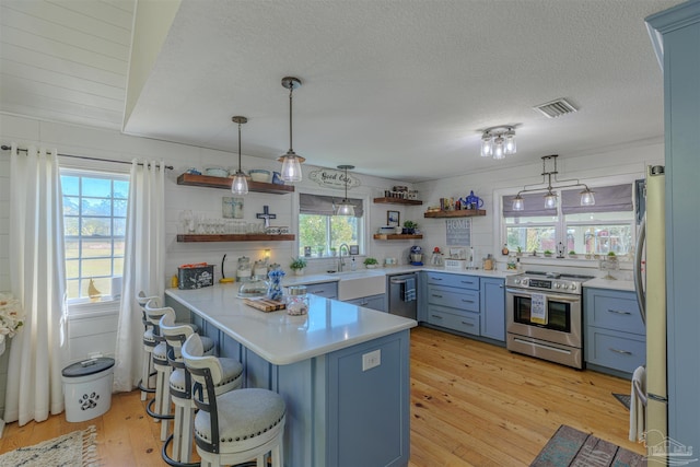 kitchen with open shelves, appliances with stainless steel finishes, a peninsula, visible vents, and light wood-style floors
