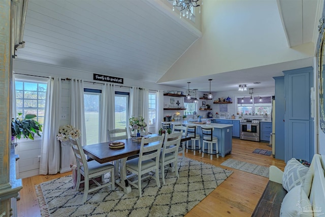 dining area featuring plenty of natural light, light wood finished floors, and high vaulted ceiling