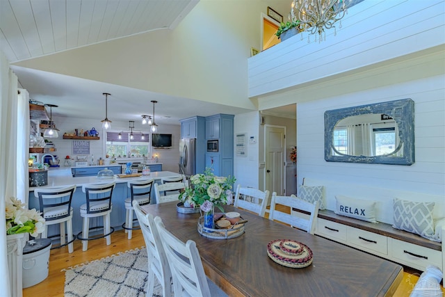 dining space featuring high vaulted ceiling and light wood-style flooring