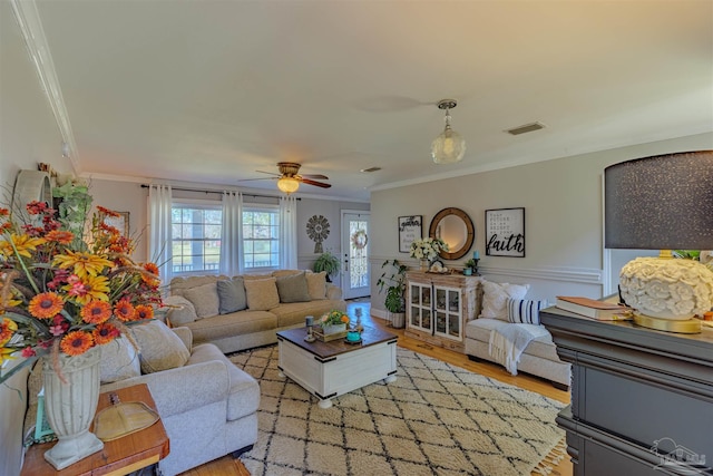 living room featuring ornamental molding, visible vents, ceiling fan, and light wood-type flooring