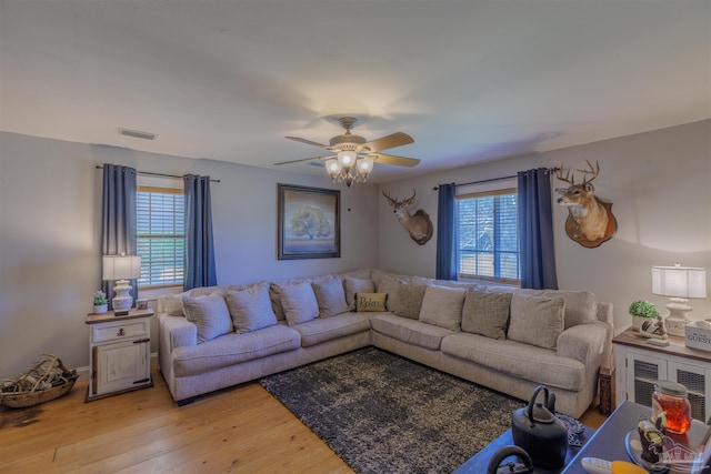living room featuring ceiling fan, visible vents, and light wood finished floors
