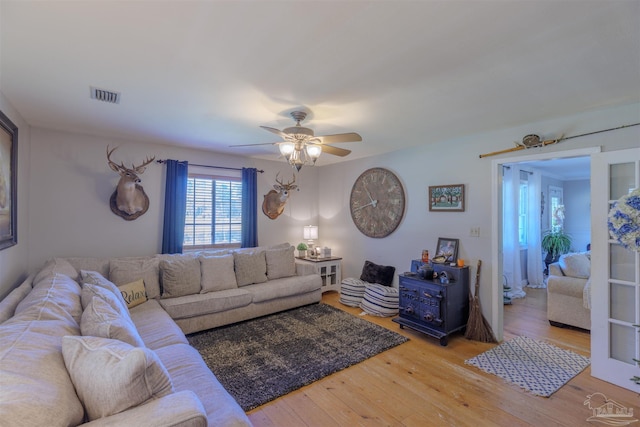 living area featuring light wood-style flooring, visible vents, and ceiling fan