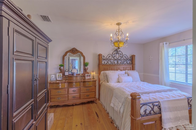 bedroom with light wood-type flooring, a notable chandelier, and visible vents