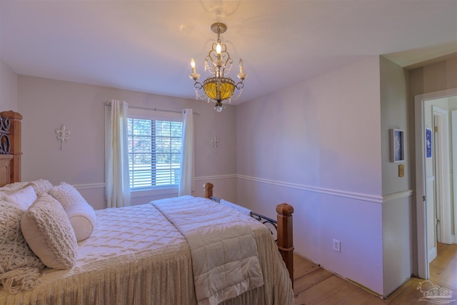 bedroom featuring an inviting chandelier and light wood-style floors