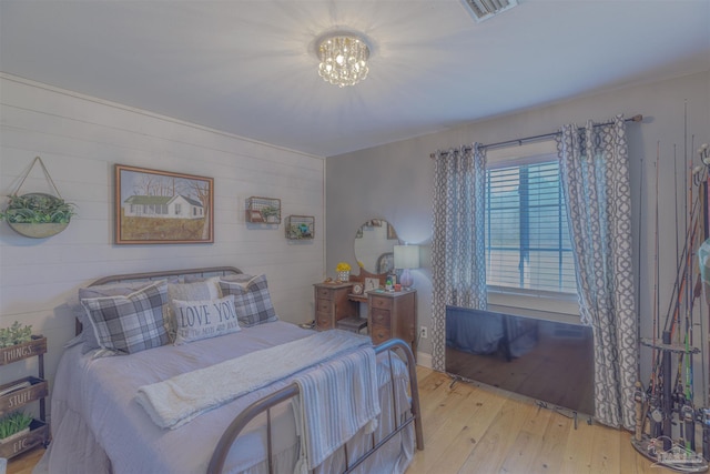 bedroom featuring visible vents, wood finished floors, and a notable chandelier