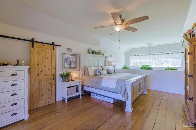 bedroom with visible vents, a ceiling fan, lofted ceiling, a barn door, and light wood-type flooring