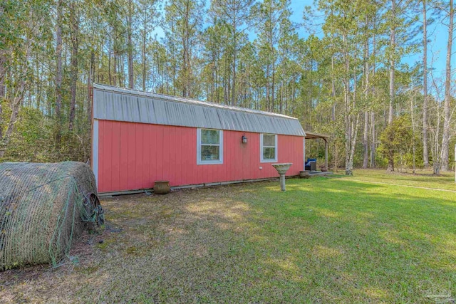 view of side of property with metal roof, an outbuilding, and a yard