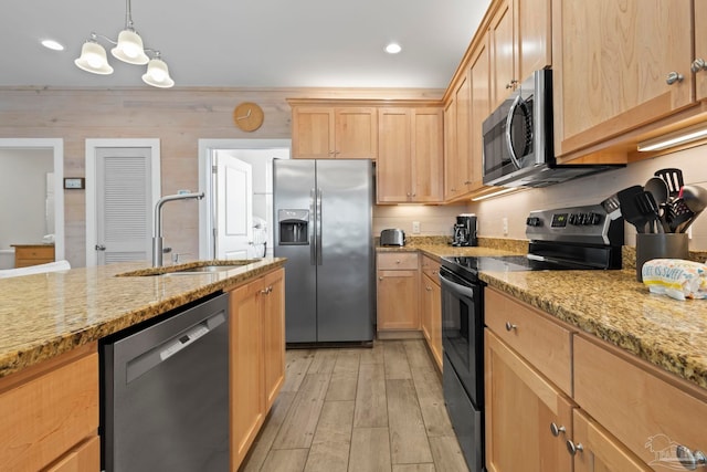 kitchen featuring sink, stainless steel appliances, light hardwood / wood-style flooring, wood walls, and decorative light fixtures