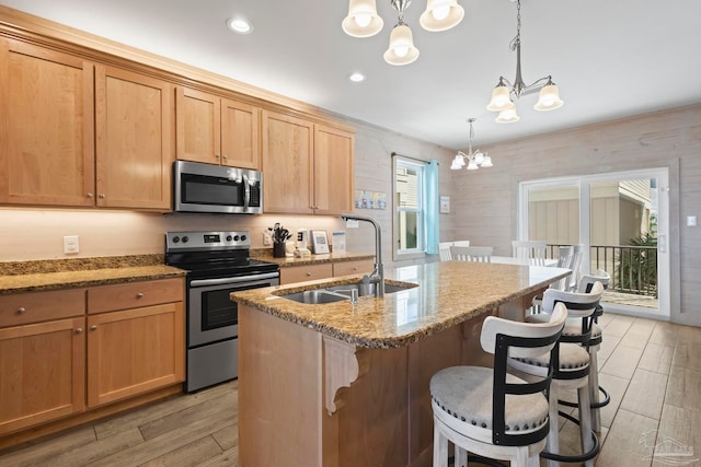 kitchen with light stone counters, stainless steel appliances, sink, pendant lighting, and an inviting chandelier