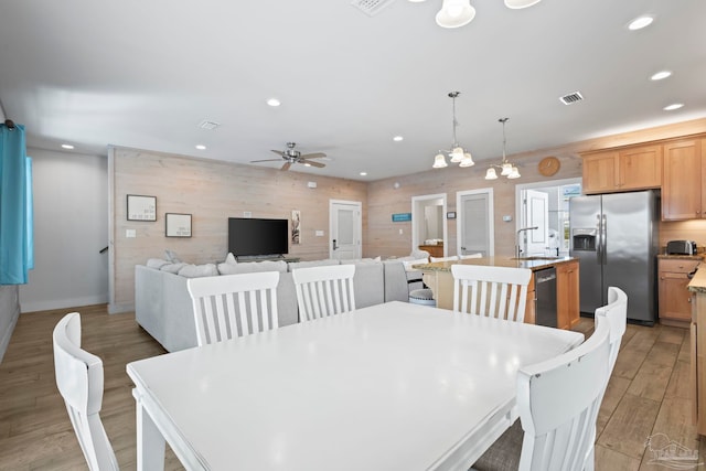 dining room featuring ceiling fan with notable chandelier, light hardwood / wood-style floors, and sink