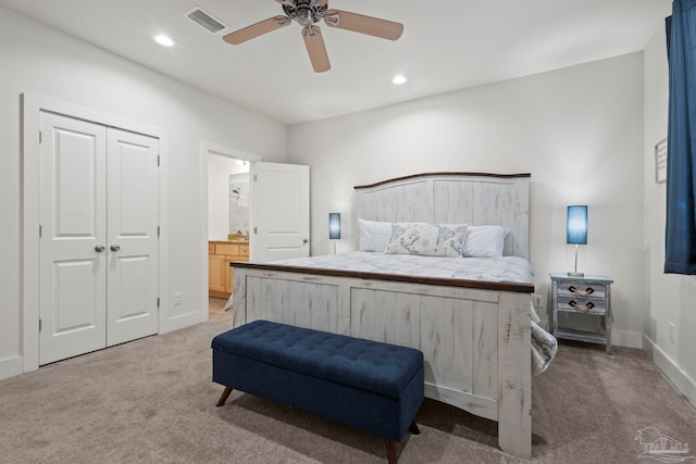 bedroom featuring ceiling fan, light colored carpet, ensuite bathroom, and a closet