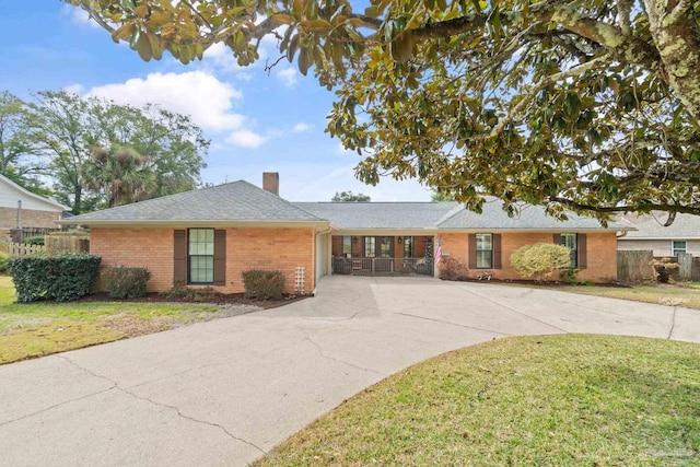 ranch-style home with brick siding, a chimney, concrete driveway, and a front yard