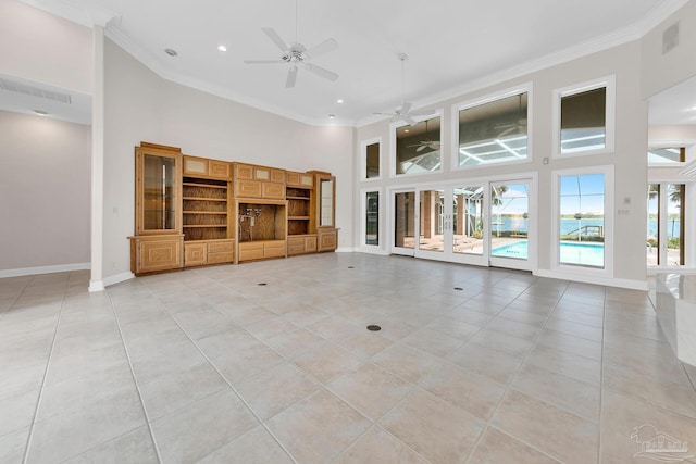 unfurnished living room with baseboards, a high ceiling, visible vents, and ornamental molding