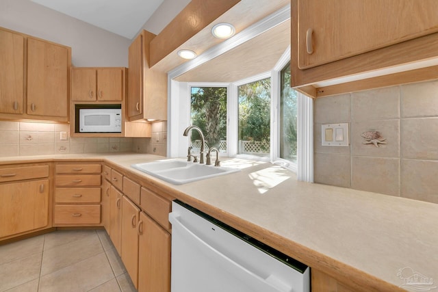 kitchen featuring white appliances, tasteful backsplash, light countertops, and a sink