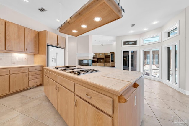 kitchen featuring white appliances, tasteful backsplash, tile counters, and light brown cabinetry