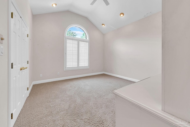 carpeted spare room featuring ceiling fan, baseboards, and vaulted ceiling