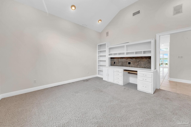 unfurnished office with baseboards, high vaulted ceiling, visible vents, and light colored carpet