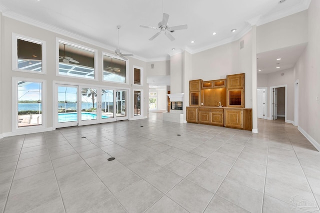 unfurnished living room featuring ornamental molding, baseboards, a high ceiling, and light tile patterned floors