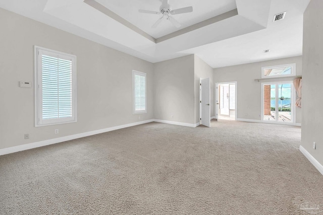 spare room with visible vents, baseboards, a raised ceiling, ceiling fan, and carpet