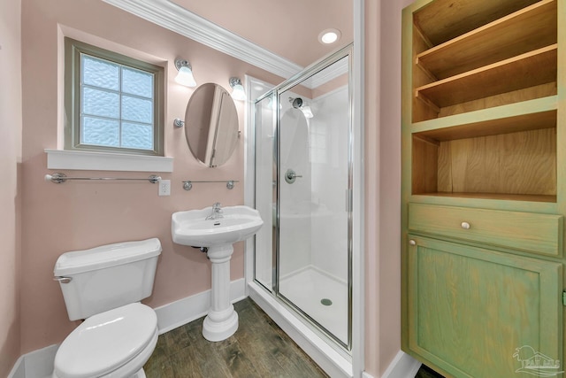 bathroom featuring toilet, a stall shower, baseboards, and crown molding