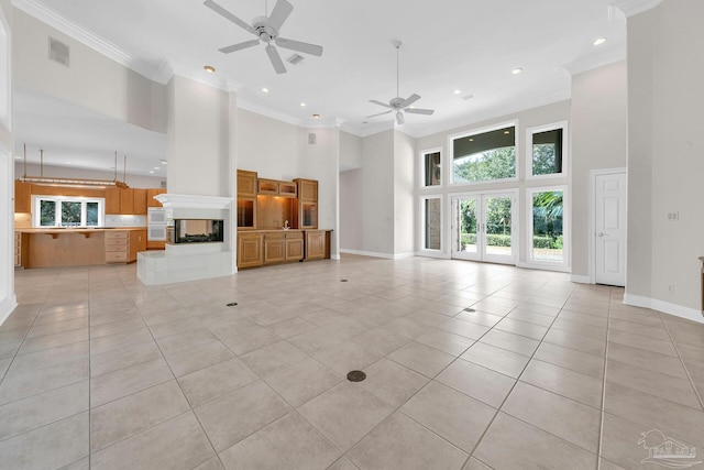 unfurnished living room with visible vents, a multi sided fireplace, a towering ceiling, and crown molding