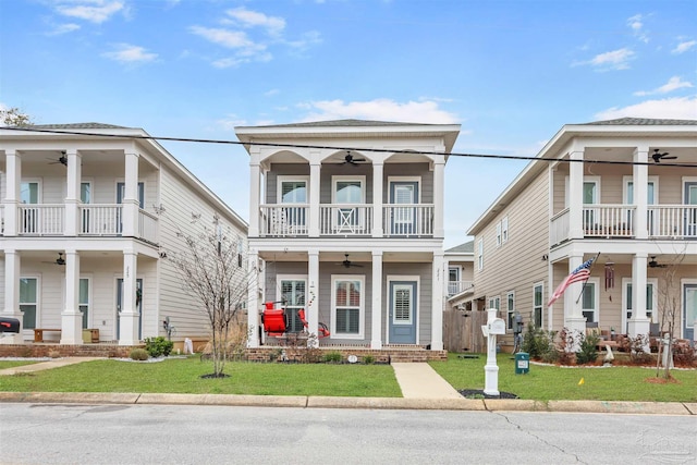 greek revival inspired property featuring ceiling fan, a front lawn, and a balcony