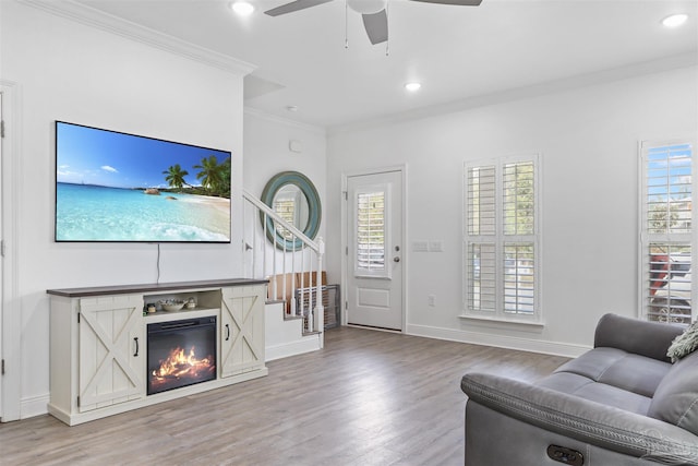 living area with recessed lighting, ornamental molding, a glass covered fireplace, wood finished floors, and baseboards