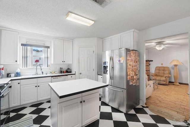 kitchen featuring stainless steel refrigerator with ice dispenser, a center island, sink, and white cabinets