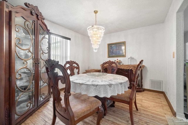 dining space featuring french doors, a chandelier, and light hardwood / wood-style flooring