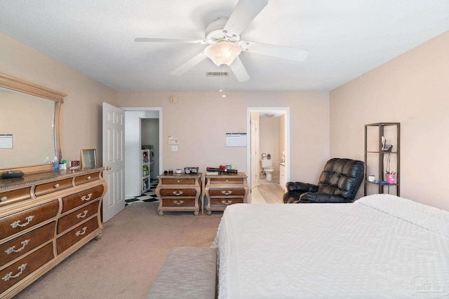 bedroom with a textured ceiling, connected bathroom, light colored carpet, and ceiling fan