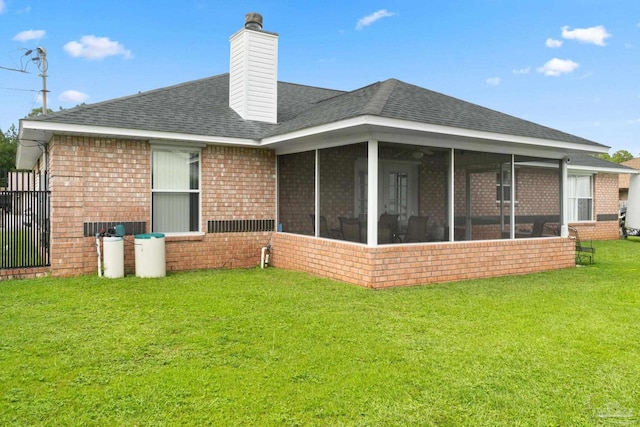 rear view of house with a yard and a sunroom