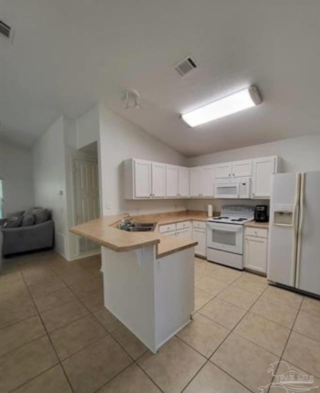 kitchen with white appliances, white cabinets, a peninsula, vaulted ceiling, and light countertops