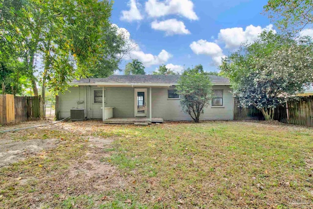 rear view of property featuring cooling unit and a yard