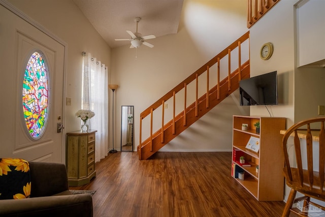 entryway with dark wood-type flooring, a high ceiling, a ceiling fan, baseboards, and stairs