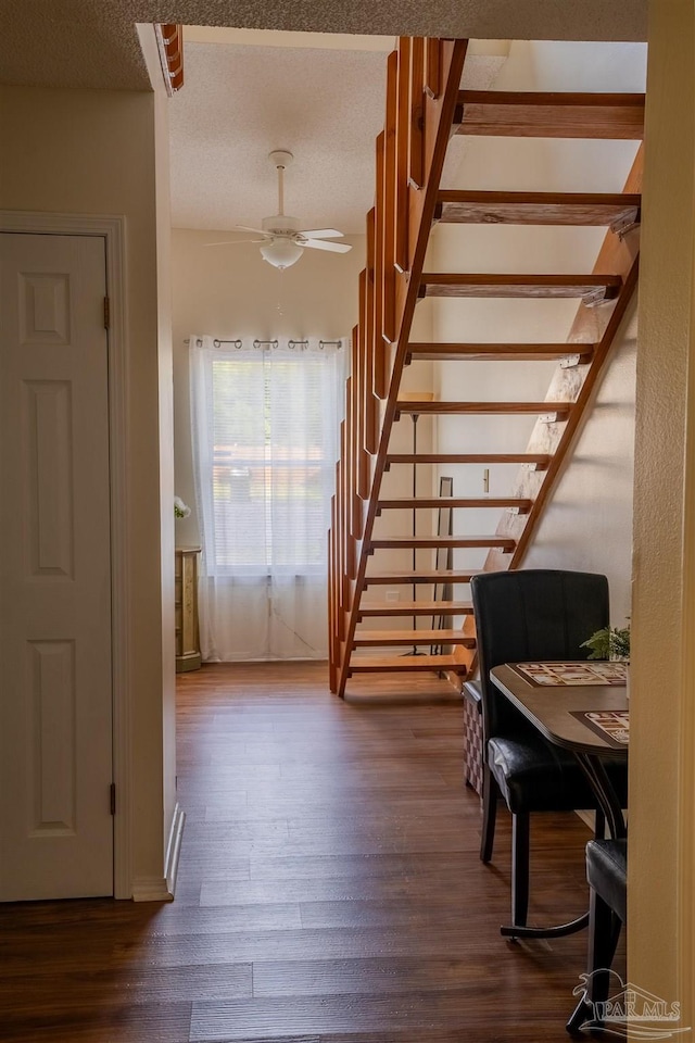 interior space with a textured ceiling, a ceiling fan, and wood finished floors