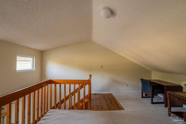 stairway with carpet floors, baseboards, a textured ceiling, and lofted ceiling