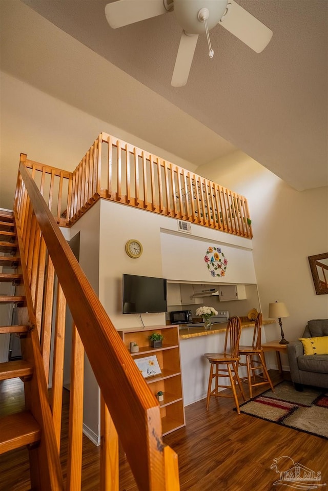 staircase with ceiling fan, wood finished floors, and visible vents