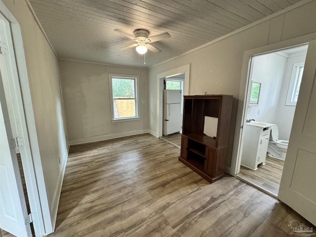 interior space with crown molding, light wood-style floors, freestanding refrigerator, wooden ceiling, and baseboards