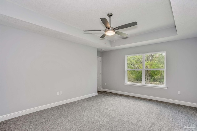 unfurnished room featuring carpet, ceiling fan, a textured ceiling, and a raised ceiling