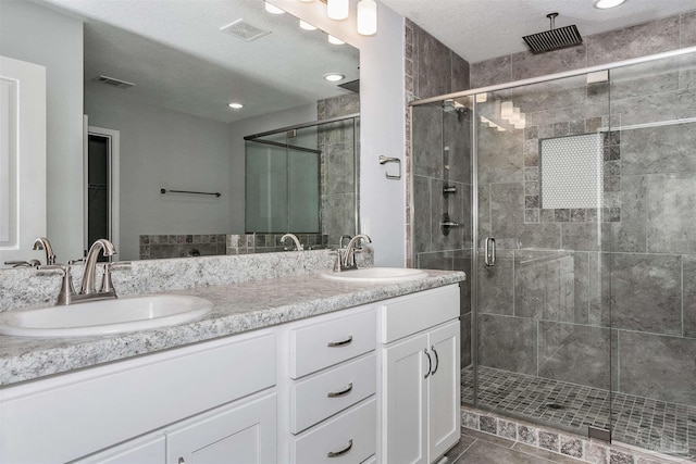 bathroom featuring a shower with door, vanity, a textured ceiling, and tile patterned floors