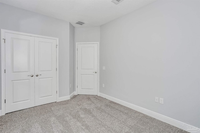 unfurnished bedroom with light colored carpet and a closet