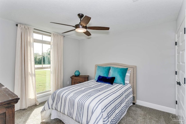 bedroom featuring ceiling fan, a textured ceiling, multiple windows, and carpet floors