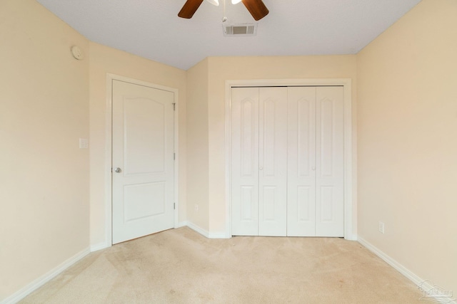 unfurnished bedroom with ceiling fan, light carpet, and a closet